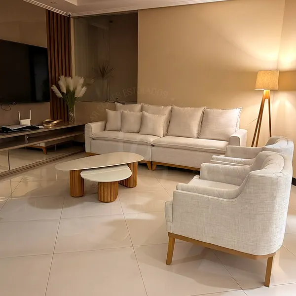 Sofá claro e duas poltronas em sala iluminada à noite
