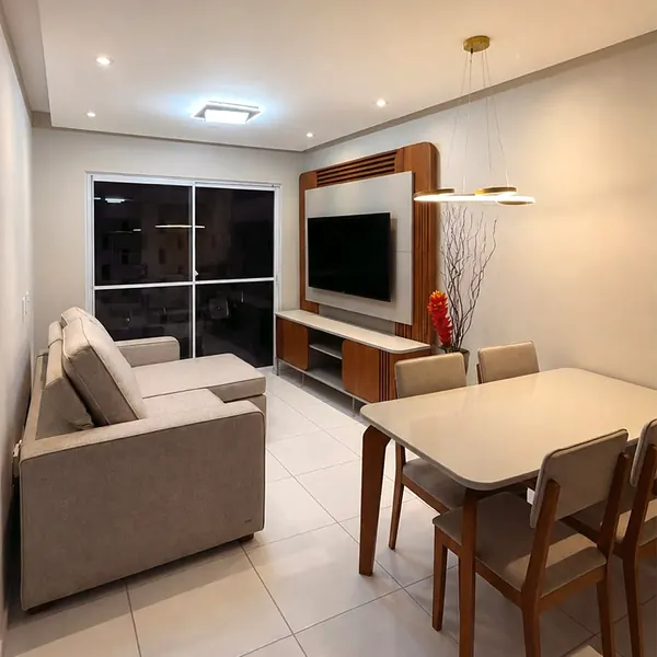 Sala com sofá com chaise, painel de TV e mesa de jantar