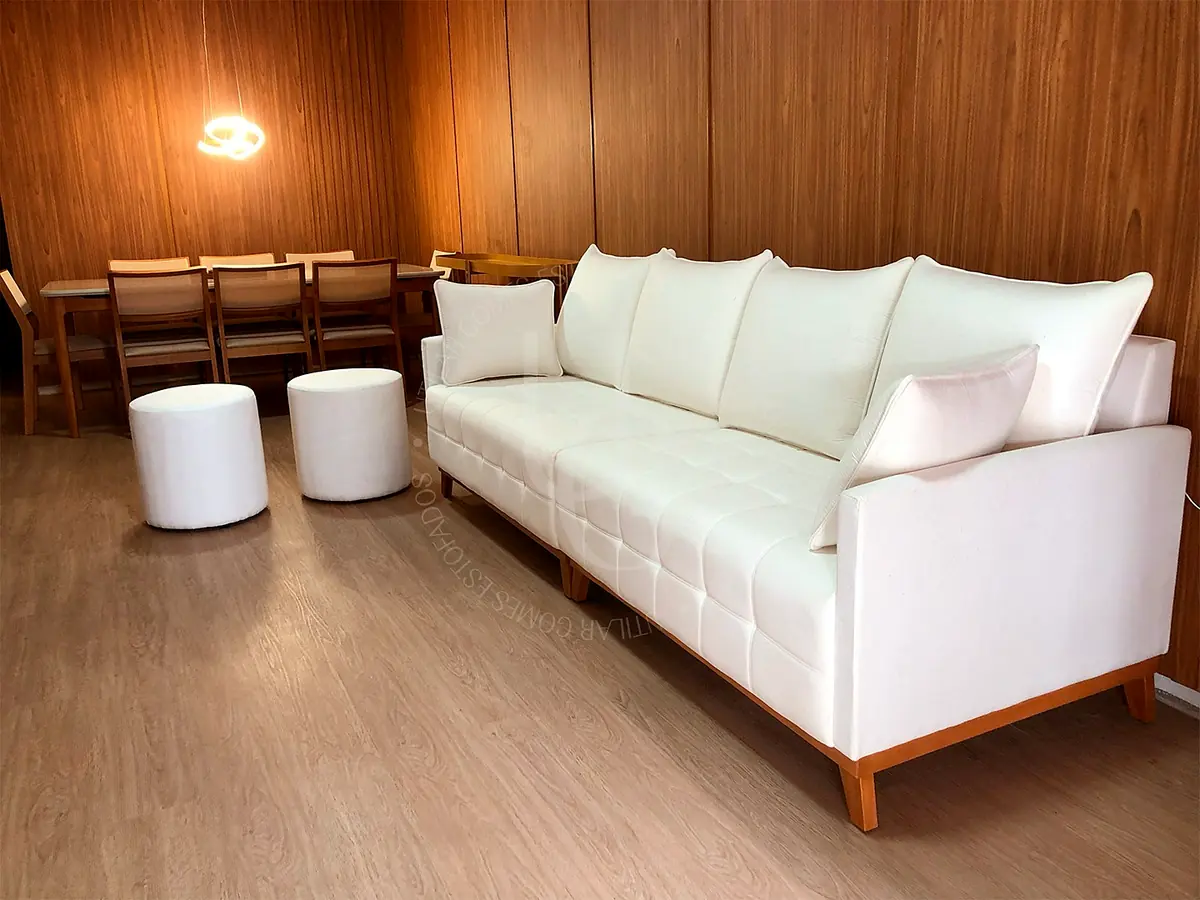 Sofá branco com base de madeira em sala com painel amadeirado, da Utilar Gomes